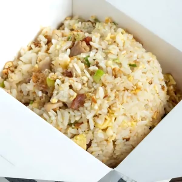 Close-up of fried rice with egg, meat, and green onions in a white takeout box from Boba Up.